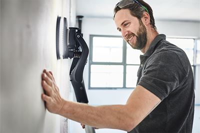 Бояджия шлайфа стена с ръчната шлифовачка с дълга дръжка Planex на Festool