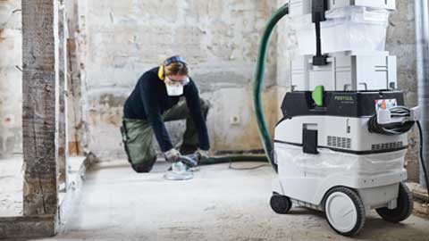 Занаячия шлайфа под и използва системата за шлайфане на подове Festool с вакуумно почистване.
